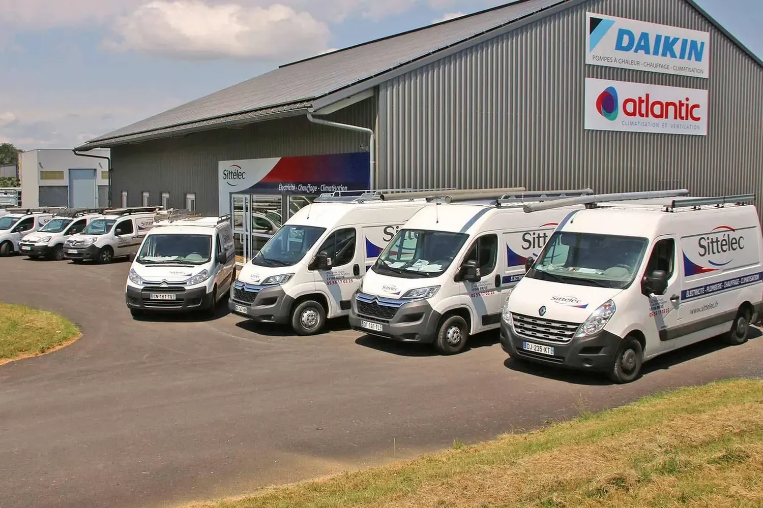 Les utilitaires Sittélec alignés devant l'atelier de Brive-la-Gaillarde, sous l'enseigne Daikin et Atlantic